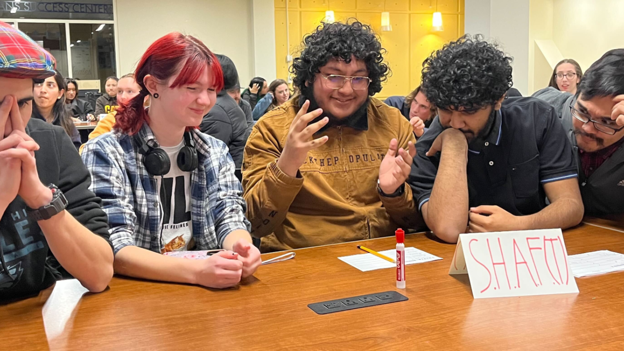 Students sitting at a table trying to answer trivia questions