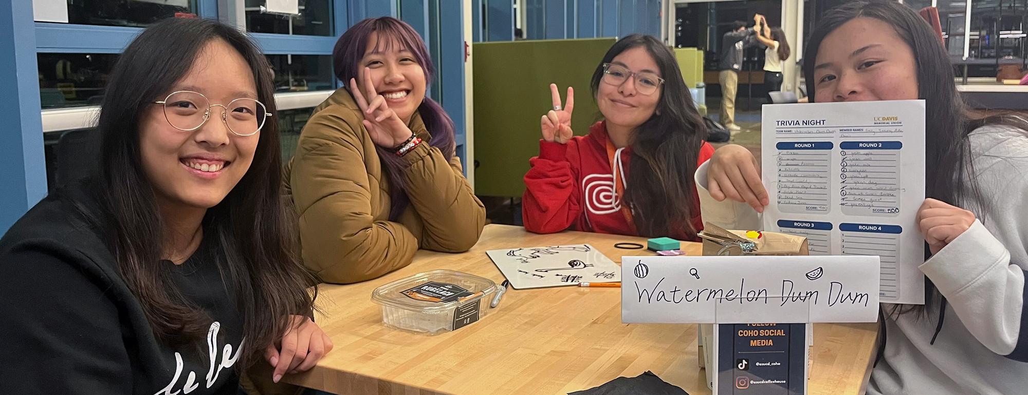 A group of students smiles and shows their trivia card