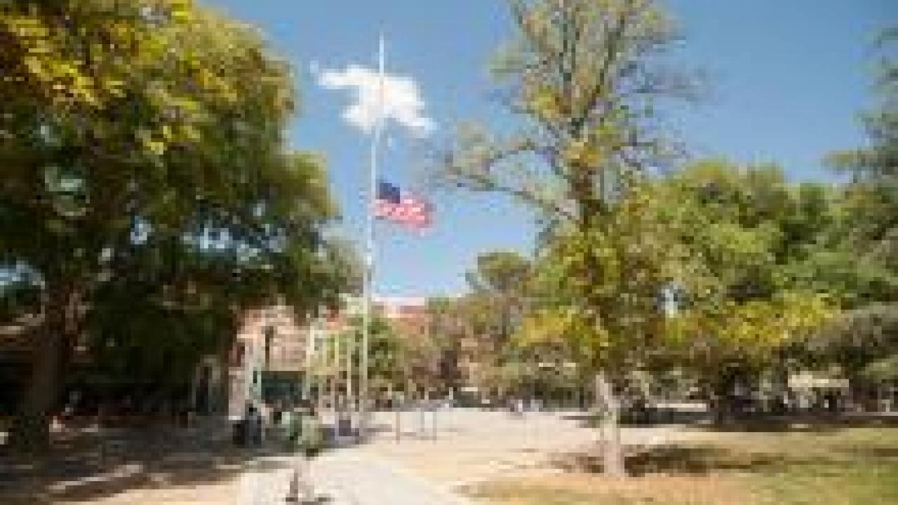US, California and University flags flown at half-staff with Memorial Union in background