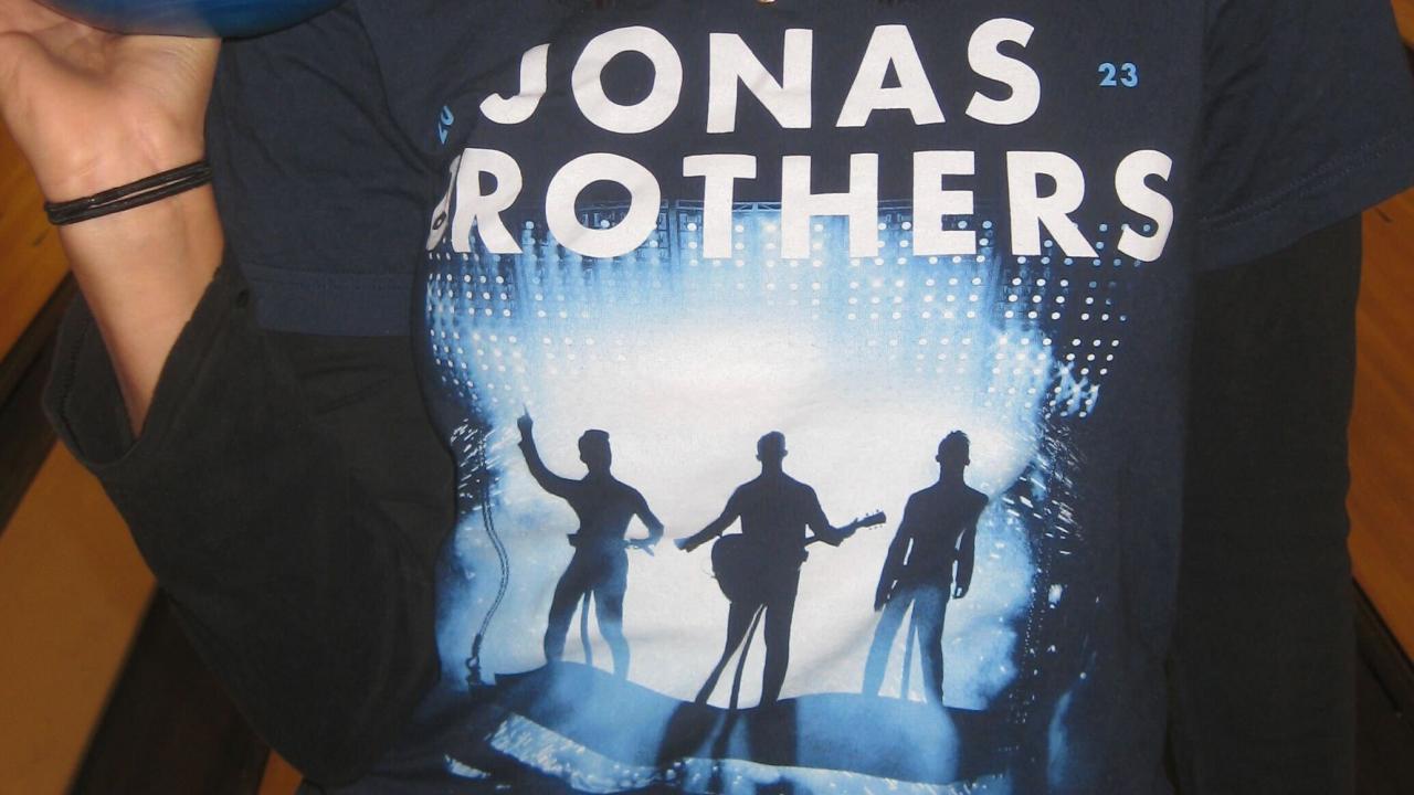 A student wearing a Jonas Brothers t-shirt poses with a bowling ball in the Games Area