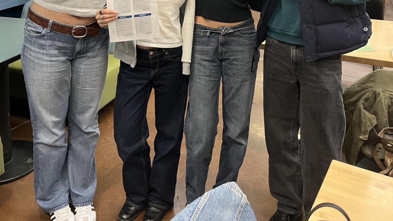 Trivia night team posing with their answer sheet and team name