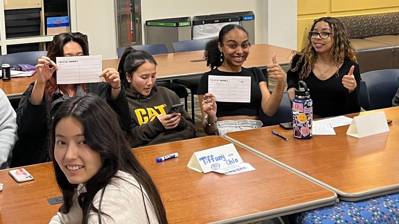 Five students hold up answers sheets and smile 