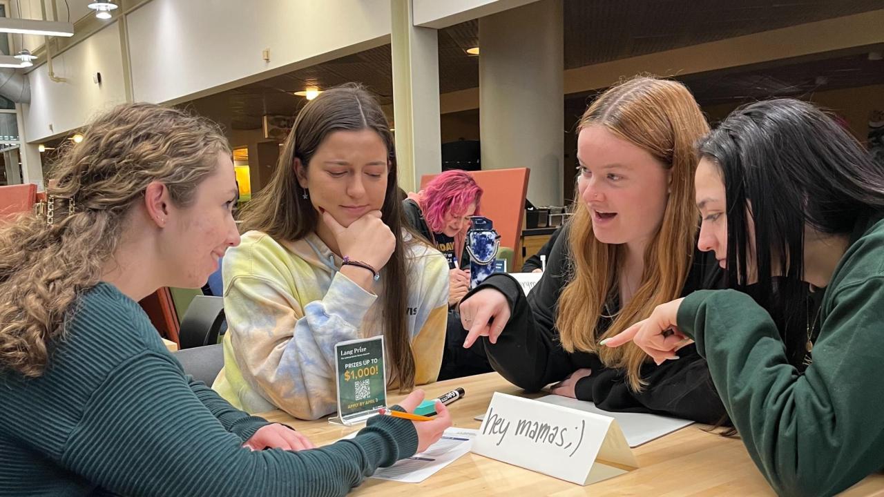 Four students work on a trivia question seated in the CoHo