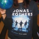 A student wearing a Jonas Brothers t-shirt poses with a bowling ball in the Games Area