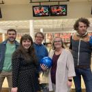 Group of 5 staff smiling in front of bowling lanes