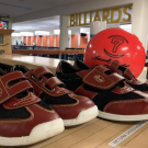 A pair of bowling shoes beside a bowling ball on the counter of the games area
