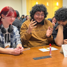 Students sitting at a table trying to answer trivia questions