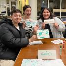Three students hold up their team name at Trivia Night