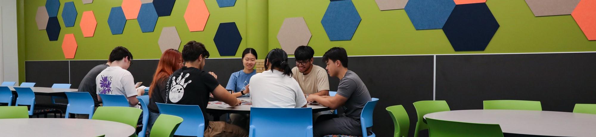 Students playing a game at a table in the games area rec room.